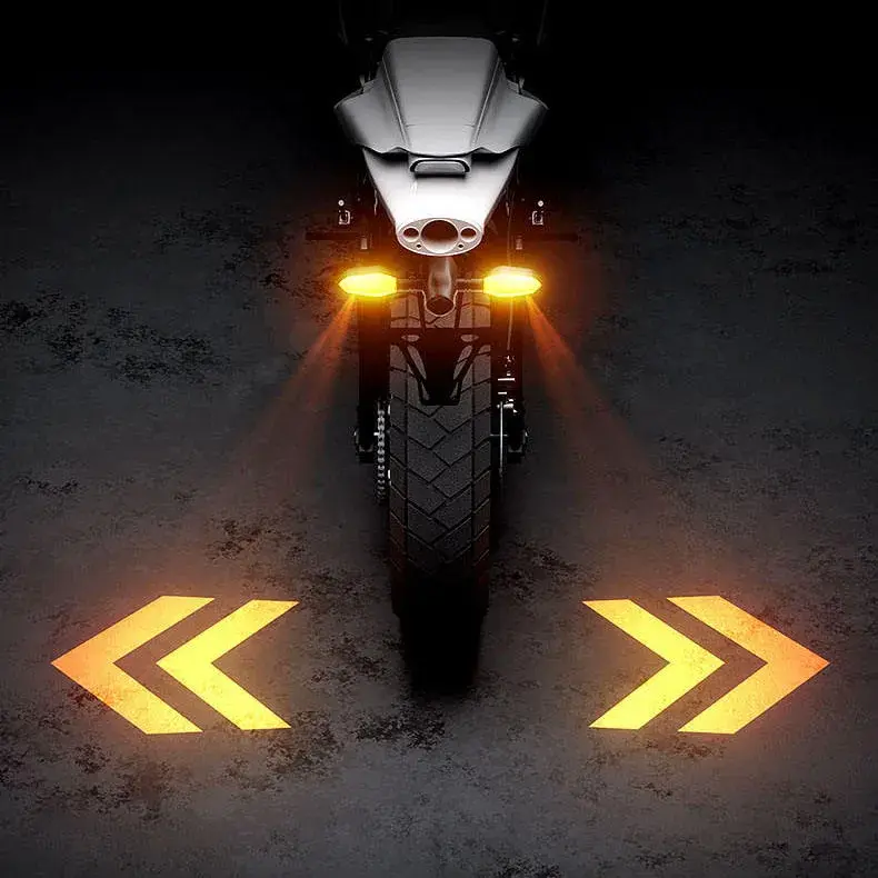 Rear view of a motorcycle projecting bright yellow double chevron arrows onto the ground