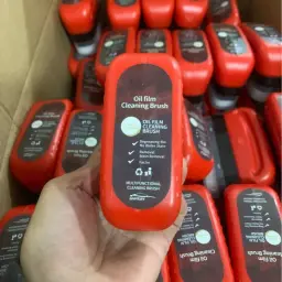 Oil Film Cleaning Brush held in hand showing the red 120ml bottle with sportcars branding
