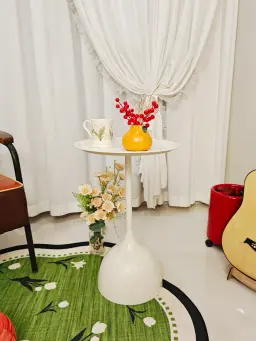 সাদা সাইড টেবিলের উপর রাখা লাল ডেকোরেটিভ বেরি সমেত উজ্জ্বল কমলা রঙের ফুলদানি