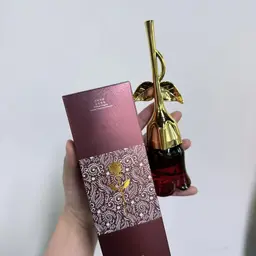 মেরুন রঙের বক্সের পাশে হাতে ধরা মিডনাইট রোজ পারফিউমের লাল গোলাপ আকৃতির বোতল